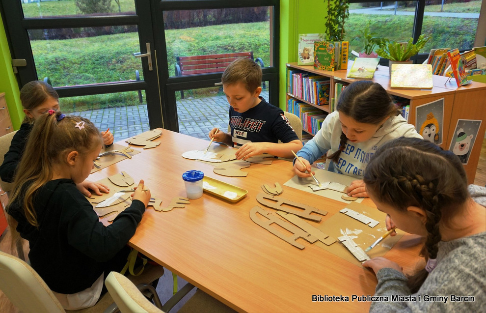 Dzieci malują na biało elementy pracy wycięte z tektury