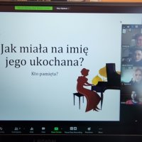 Kolejny slajd z prezentacji, widać kształt przypominający dwa łabędzie oraz kobietę przy fortepianie.