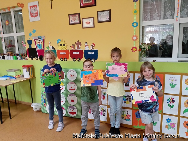 Czwórka dzieci prezentuje swoje prace wykonane na zajęciach.