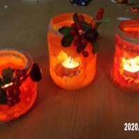 Na blacie stołu umieszczono trzy pomarańczowe lampiony ozdobione sznurkiem, jarzębiną i kasztanami. Przez niepomalowaną powierzchnię w kształcie liścia widać w środku zapalone świeczki. 