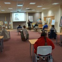 Sala z zebranymi uczestnikami spotkania, widać dziesięć osób siedzących przy stolikach.