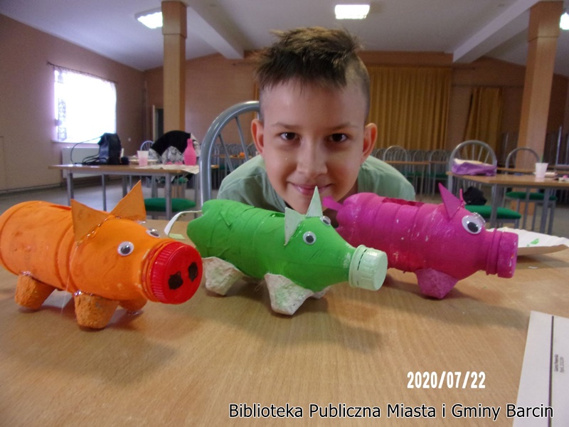 Chłopiec pozuje do zdjęcia z trzema świnkami skarbonkami.
