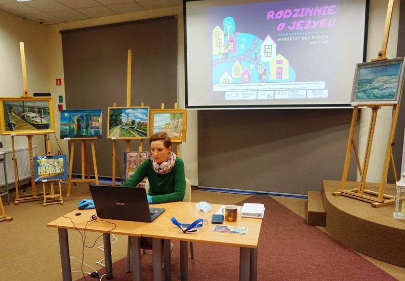 Osoba prowadząca warsztat "Rodzinnie o języku" siedzi przy komputerze.