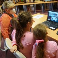 Mama z trzema córkami, uczestniczki warsztatu dla rodzin Rodzinnie o języku on-line siedzą przed komputerem.