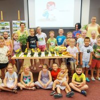Grupowe zdjęcie uczestników zajęć zebranych wokół stołu, na którym leżą doniczki z zasadzonymi cytrynami.