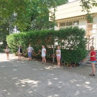 Szóstka dzieci stojąca przed budynkiem świetlicy, trzyma łańcuch z kół zrobiony z kolorowych patyczków.