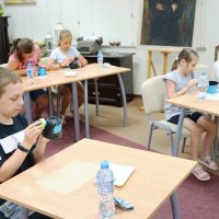 Dzieci korzystając z gąbek, malują doniczki na niebiesko.
