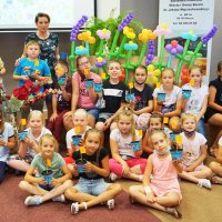 Grupowe zdjęcie uczestników, dzieci trzymają doniczki z nasionami.