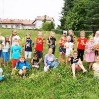 Zdjęcie grupowe dzieci po udanych zbiorach, szósta dzieci siedzi lub kuca w pierwszym rzędzie pozostała szesnastka stoi za nimi.