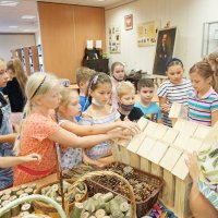 Dzieci wybierają szkielet domku dla owadów, który jest wykonany z drewna i ma kształt prostokąta z trójkątnym dachem.