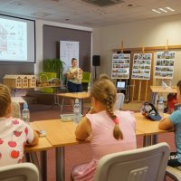 Pani bibliotekarka tłumaczy dzieciom budowę domku i wyjaśnia jakie owady chętniej skorzystają z danego rodzaju wypełnienia.