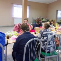 Uczestniczki spotkania siedzą przy stołach i szydełkują.