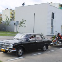Na zdjęciu widać czarny samochód marki Wołga z lawetą, na której stoją dwa motocykle.