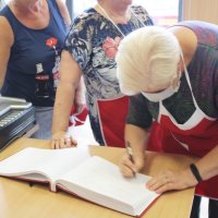 Panie z koła gospodyń wiejskich wpisują się do księgi pamiątkowej w bibliotece.