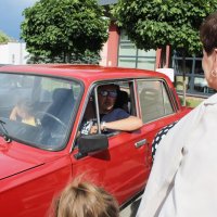 Na zdjęciu widać chłopca i dorosłego mężczyznę siedzących w Fiacie 125p, mężczyzna rozmawia z dyrektorem barcińskiej biblioteki.