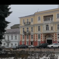 Kadr z filmu, na którym widać budynek o żółto czerwonej elewacji, białych zdobionych gzymsach i wysokich oknach.
