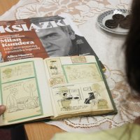 Na zdjęciu widać zeszyt wypełniony różnymi ilustracjami, które wyglądają na dowcipy, zeszyt jest przeglądany przez jedną z uczestniczek spotkania.