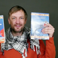 Zrzut ekranu z transmisji na żywo, widoczny na nim autor Pan  Michał Szulim prezentuje swoje dwie książki.