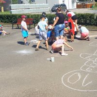 Dzieci korzystając z kredy malują grę w klasy.