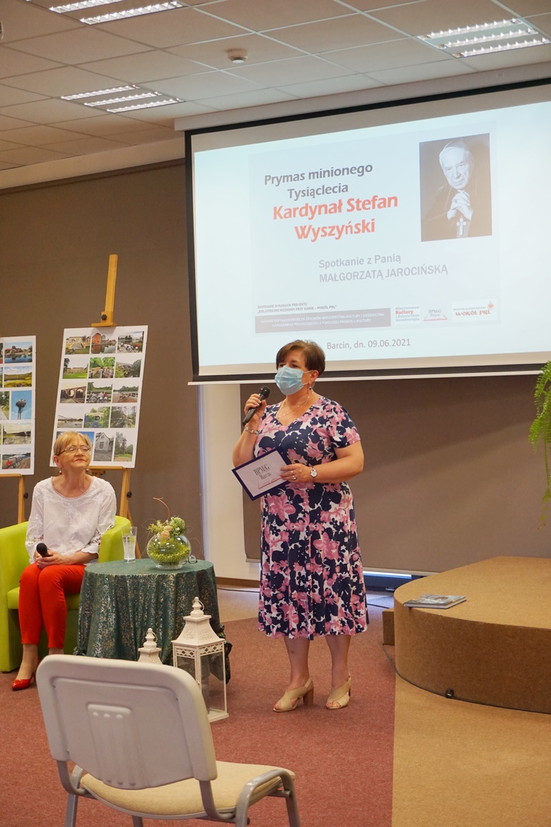 Dyrektor biblioteki wita zebranych gości, Pani MAłgorzata siedzi na fotelu.
