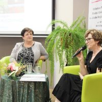 Dyrektor biblioteki Grażyna Szafraniak, oraz autorka zdjęć prezentowanych na wernisażu pani Grażyna Błaszkiewicz, siedzą na scenie i rozmawiają między sobą.