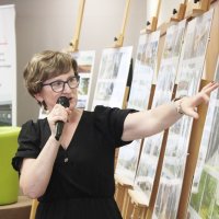 Panie Grażyna Szafraniak i Grażyna Błaszkiewicz rozmawiają o fotografiach, uczestniczka spotkania widoczna na zdjęciu przysłuchuje się im uważnie.