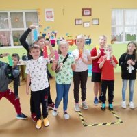 Grupowe zdjęcie dzieci biorących udział w zajęciach, wszystkie dzieci trzymają wykonane zakładki do książek.