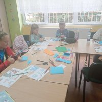 Grupa dzewczynek pracujących na zajęciach wycina niebieskie słonie z papieru.