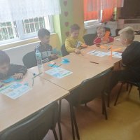 Grupa chłopców pracujących na zajęciach wycina niebieskie słonie z papieru.