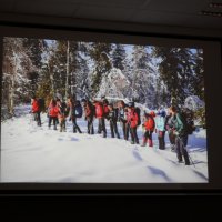 Zdjęcie z prezentacji pana Leszka Szczasnego pokazujące zimowy krajobraz i idącą grupę ludzi. 