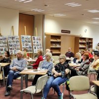 Zajęcie publiczności, widać na nim osoby siedzące na krzesłach i słuchające zaproszonej autorki.