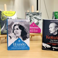 Wystawka książek Anny Kamińskiej, książki z kolorowymi okładkami ustawione są na stole oraz na miniaturowych sztalugach.