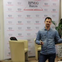 Maciej Piera ubrany w jeansową koszulę i jeansowe spodnie stoi przed sceną i rozmawia z młodzieżą.