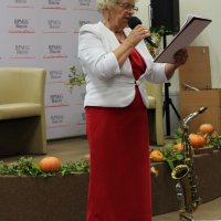 Pani Helena Wyrzykowska stoi z mikrofonem w ręce i czyta wiersz.