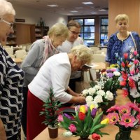 Pani Helena podpisuje się w kronice pamiątkowej, za nią w kolejce czekają uczestnicy spotkania.