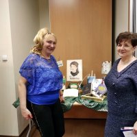 Zdjęcie Pani Iwony Kienzler i dyrektor bibloteki Pani Grażyny Szafraniak stojących z uśmiechem przy wystawce książek.