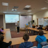 Kolejni uczniowie z innej klasy siedzą przy stołach i biorą udział w lekcji bibliotecznej.