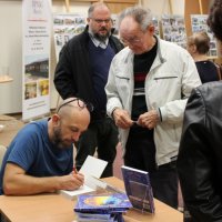 Robert Robb Maciąg składa autograf w książce jednego z widzów.