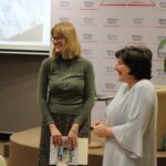 Zaproszona podróżniczka - Monika Zakrzewska razem z dyrektorką biblioteki Renatą Grabowska uśmiechnięte stoją zwrócone w stronę publiczności