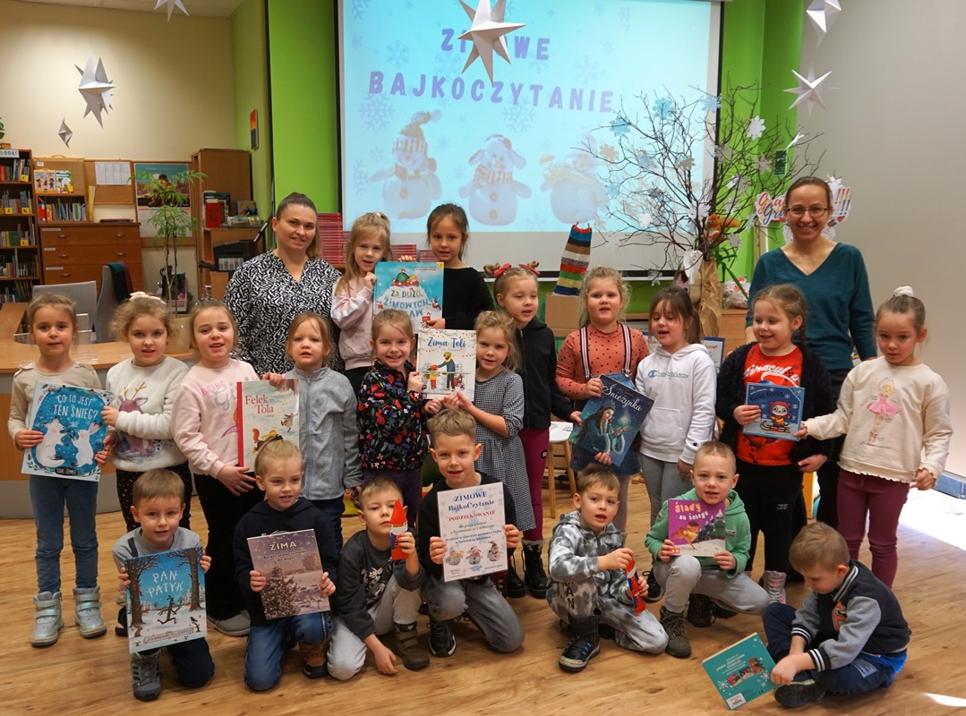 grupowe zdjęcie dzieci i opiekunów część dzieci trzyma książki czytane na zajęciach