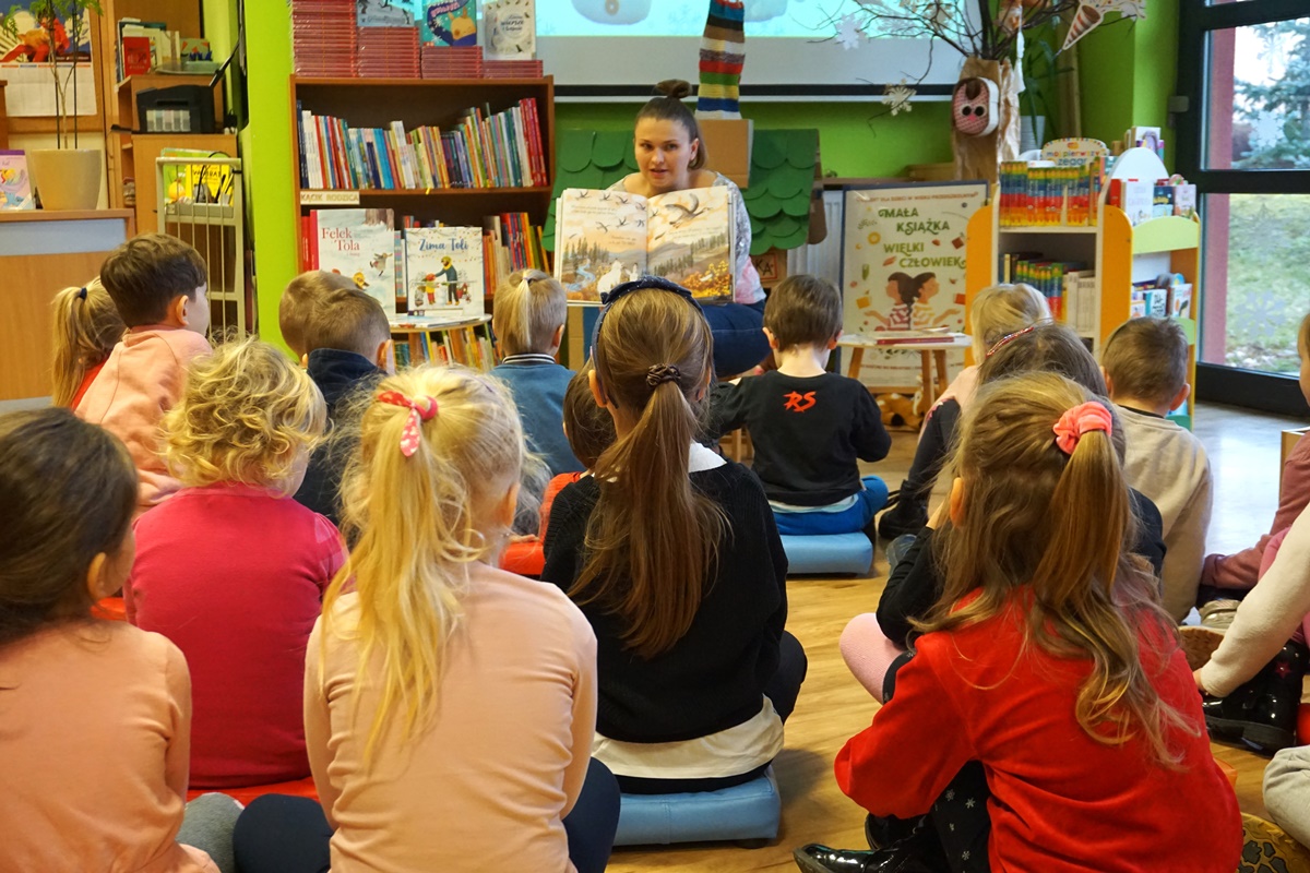 bibliotekarka czyta książkę dzieciom które przyszły na zajęcia