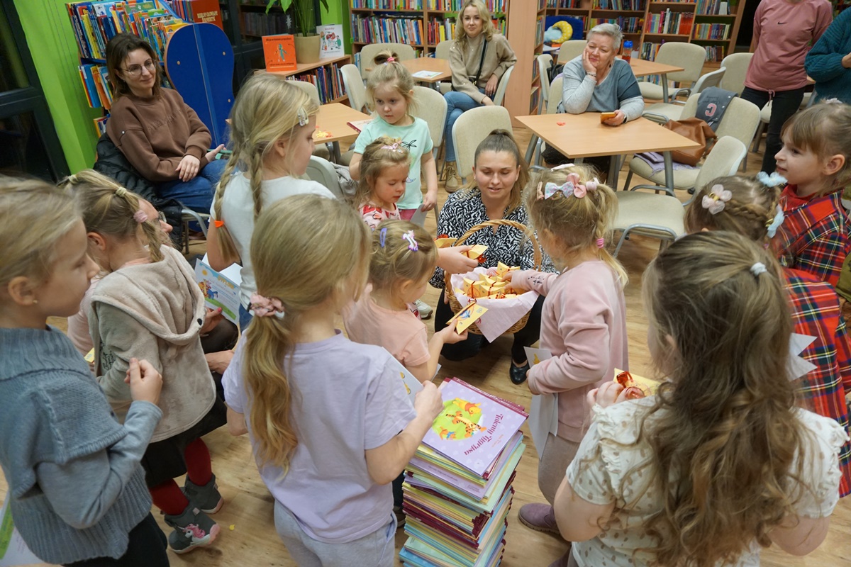 grupa dzieci, każde z nich sięga z wiklinowego koszyka upominek przygotowany przez panie bibliotekarki