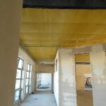 Wnętrze budynku podczas prac budowlanych, betonowe posadzki, nieotynkowanemury, żółta folia pod sufitem
