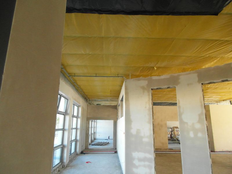 Wnętrze budynku podczas prac budowlanych, betonowe posadzki, nieotynkowanemury, żółta folia pod sufitem