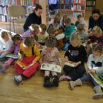 dzieci siedzą z otwartymi na kolanach książkami