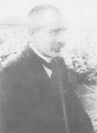 Czarno białe zdjęcie przedstawiające patrona biblioteki Jakuba Wojciechowskiego, starszy mężczyzna obcięty na jeżyka z wąsem ubrany w garnitur.