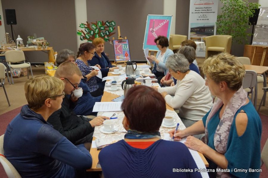 Zebrani uczestnicy rozmawiają o książce, popijają kawę i herbatę.