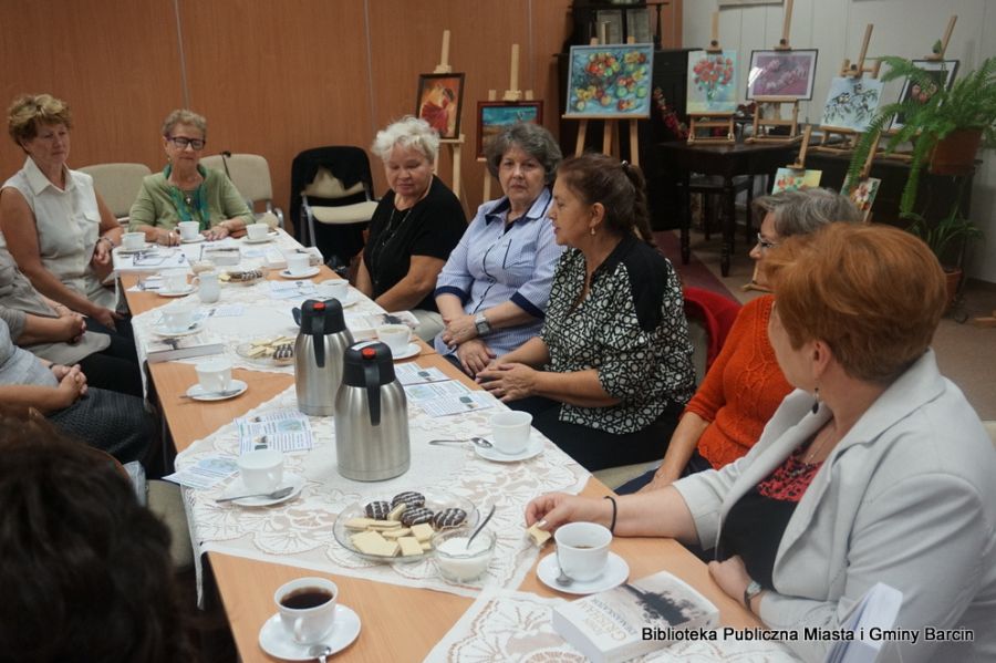 7 uczestniczek spotkania siedzących przy stołach rozmawia między sobą