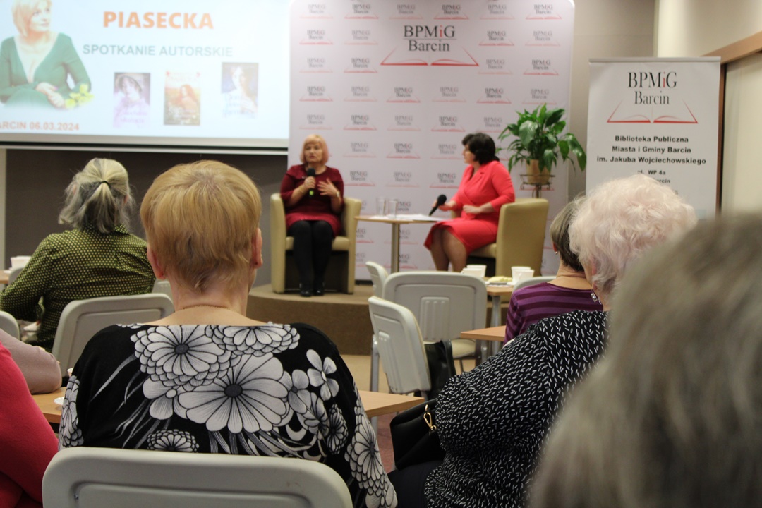 zdjęcie z perspektywy publiczności pokazujące autorkę, oraz dyrektorkę biblioteki siedzące w fotelach na scenie.