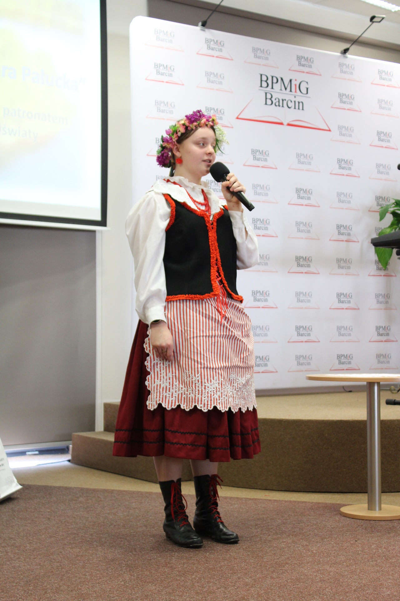 Dziewczyna w tradycyjnym pałuckim stroju ludowym występuje przed publicznością.